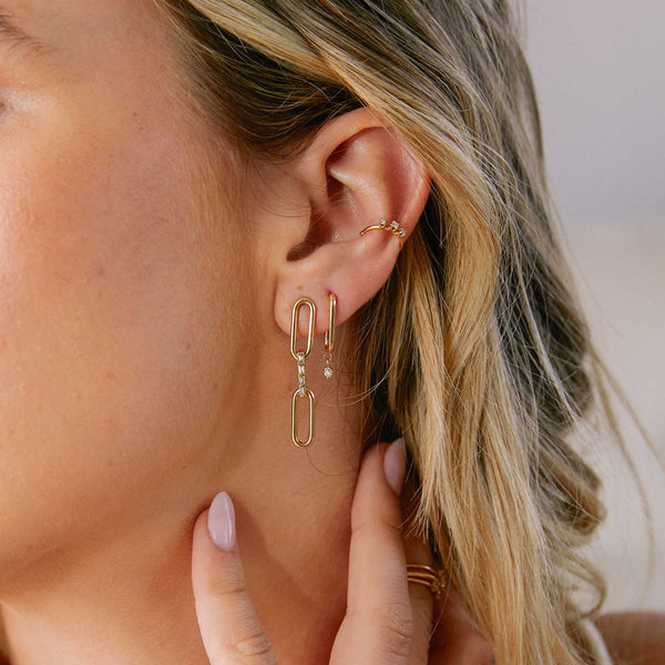 close up of woman's ear wearing a Zoë Chicco 14k Gold Large Paperclip Chain with Baguette Diamond Link Drop Earrings layered with a diamond link earring and a graduated prong diamond ear cuff