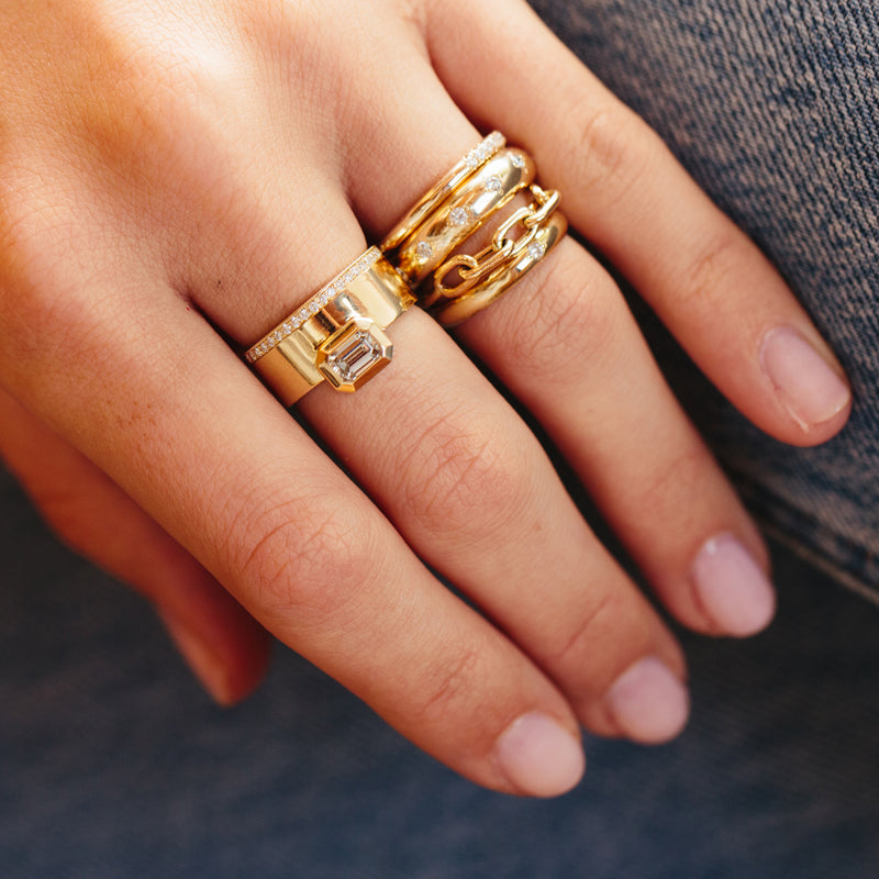 woman's hand wearing Zoë Chicco 14kt Gold Square Oval Link Chain Ring stacked with other gold and diamond rings