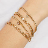 woman's wrist wearingZoë Chicco 14k Small Gold Bead Bracelet with Midi Bitty Heart Charm layered with three other bracelets