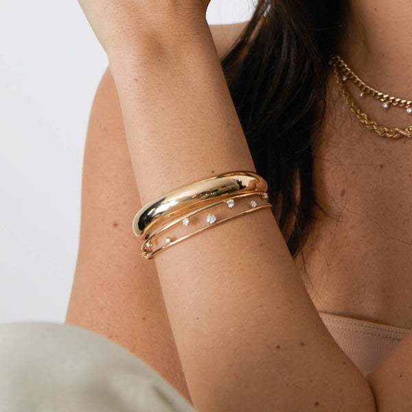 woman's arm wearing a Zoë Chicco 14kt Gold Prong Diamond Double Band Cuff Bracelet and Medium Aura Cuff Bracelet on her wrist