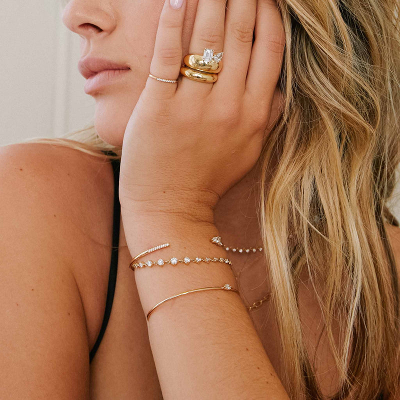 woman wearing a Zoë Chicco 14k Gold Linked Graduated Prong Diamond Tennis Bracelet layered with two bracelets resting her hand on her face