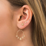 woman's ear wearing a Zoë Chicco 14k Gold Itty Bitty Pavé Diamond Disc Stud Earring layered with other disc style earrings