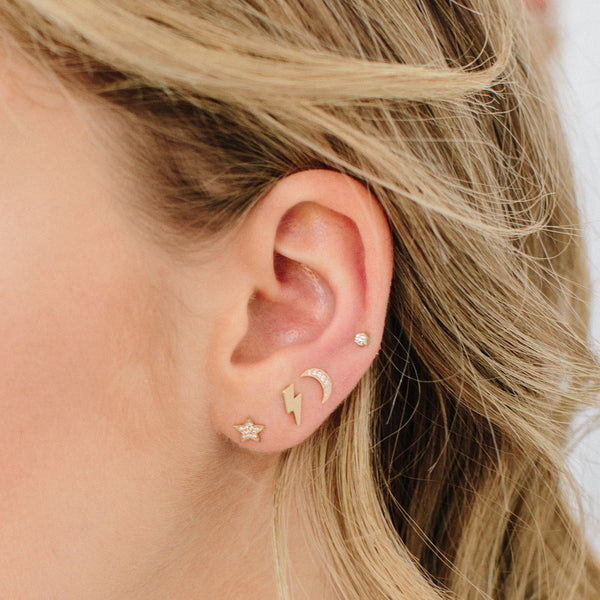 woman's ear wearing a Zoë Chicco 14k Gold Midi Bitty Lightning Bolt Stud Earring in her second piercing