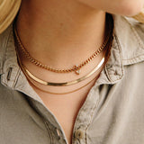 woman in olive shirt wearing a Zoe Chicco 14k Gold Extra Small Curb Chain Necklace layered with a Herringbone Chain and two other necklaces