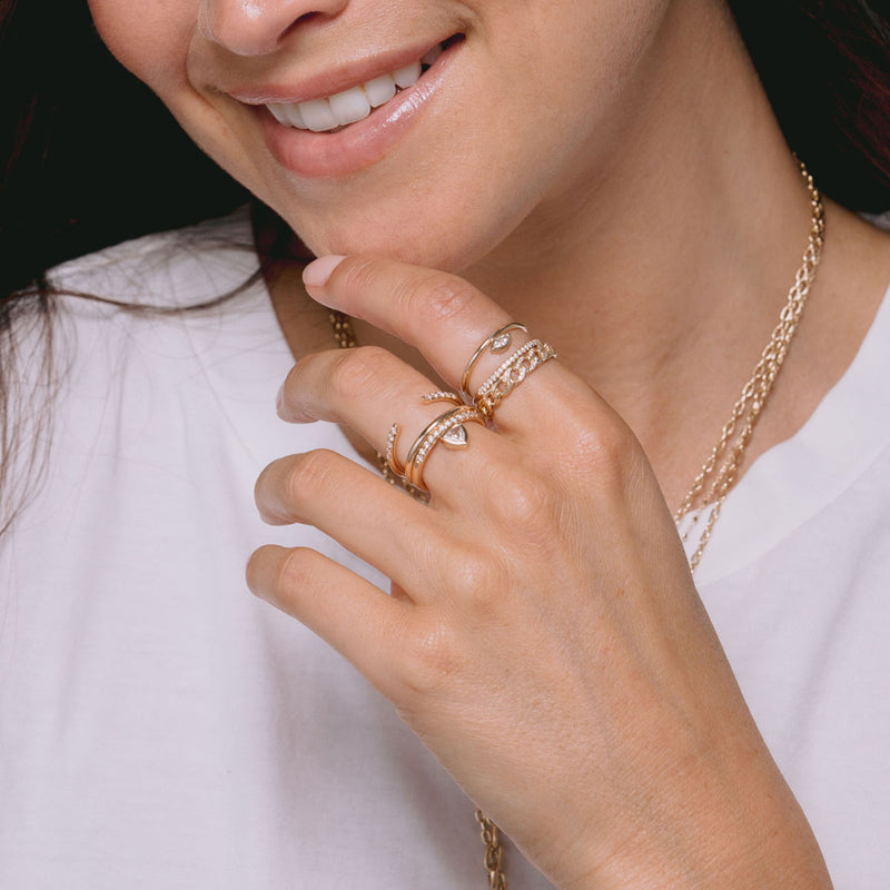 woman in white t-shirt with hand resting on chin wearing Zoë Chicco 14k Gold Pavé Diamond Solid Medium Curb Chain Band Ring on her index finger