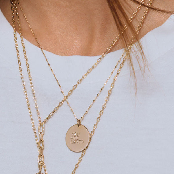 close up of woman in white shirt wearing Zoë Chicco 14k Gold Medium " YOU ARE LOVED" with Diamonds Disc Pendant Square Bead Chain Necklace around her neck