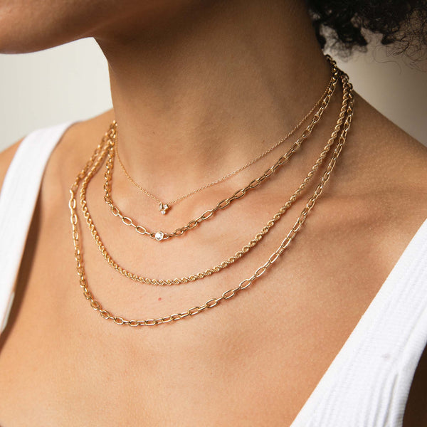 woman in white tank top wearing a Zoë Chicco 14k Gold Mixed Cut Diamond Cluster Necklace layered with a Medium Square Oval Link Necklace with Floating Diamond and a Medium Rope & Square Oval Link Chain Layered Necklace