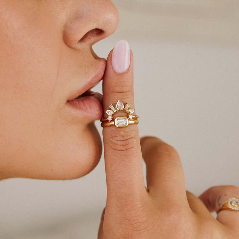 woman with her index finger touching her lips wearing a Zoë Chicco 14k Gold Mixed Cut Diamond Bezel Curved Bar Ring