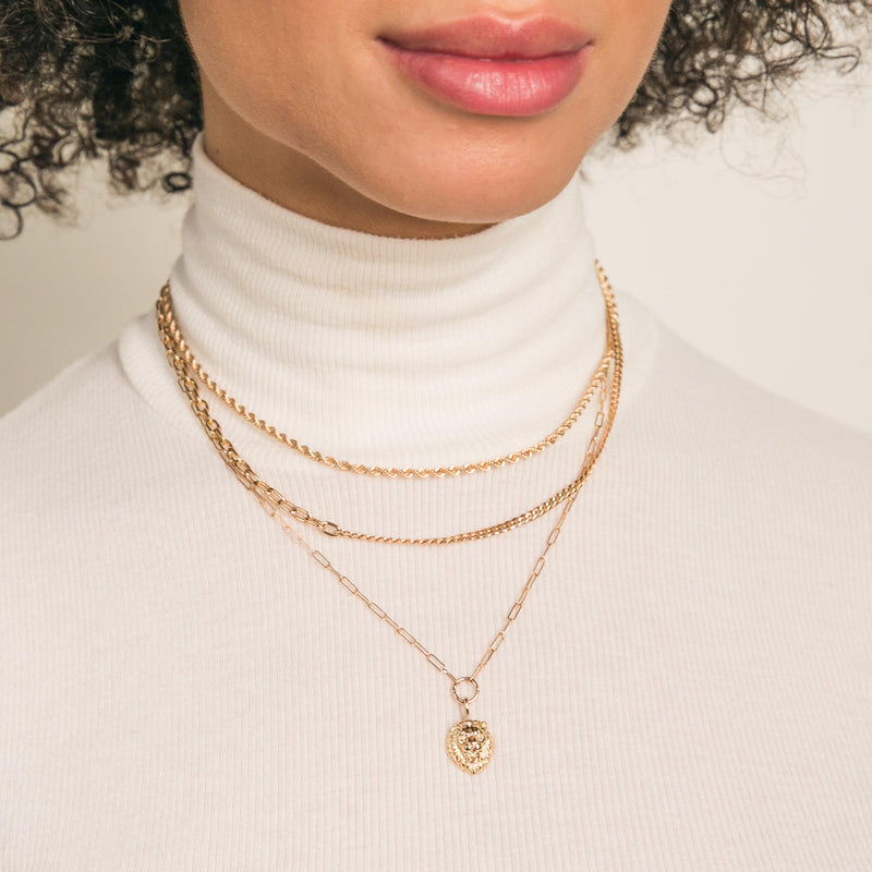 close up of woman in white turtleneck sweater wearing Zoë Chicco 14k Gold Mixed Small Curb & Medium Square Oval Link Chain Necklace layered with a Medium Rope Chain and a Lion Head Pendant Paperclip Chain Necklace