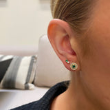 close up of woman's ear wearing Zoe Chicco 14kt Gold Round Emerald and Diamond Halo Stud Earrings