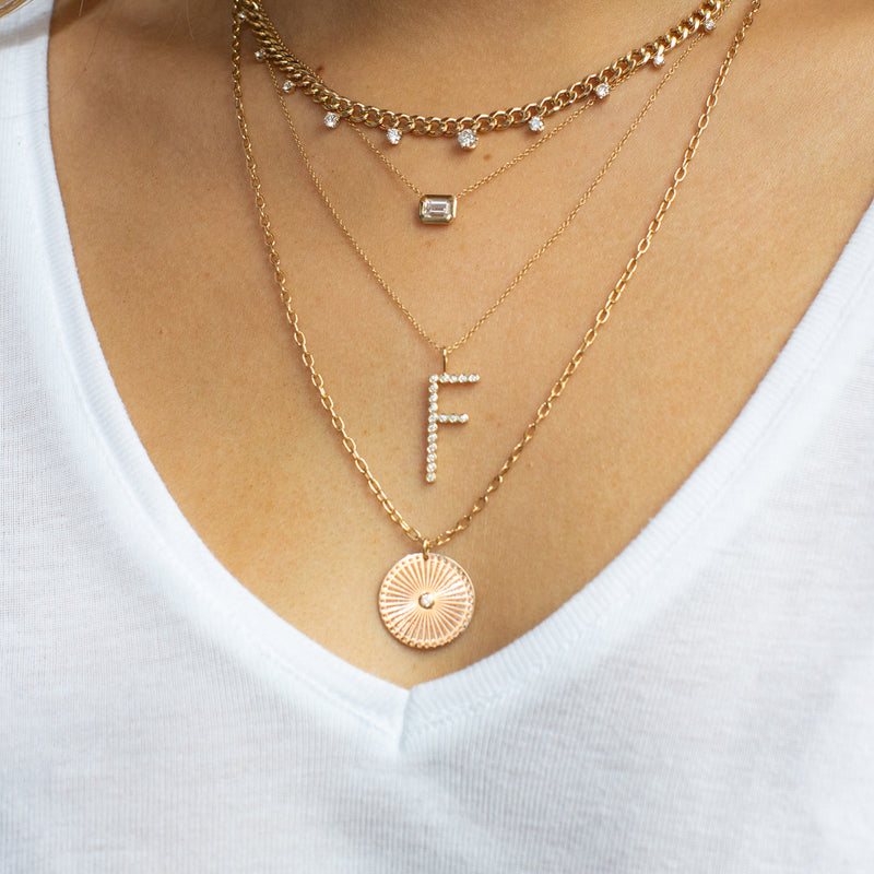 woman's neck wearing Zoë Chicco 14kt Gold Medium Sunbeam Medallion on Square Oval Chain layered with three other necklaces