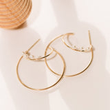 Zoë Chicco 14kt Gold Three Tiny Pearl Double Wire Medium Hoops laying on a table