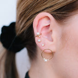 woman with her hair tied up wearing Zoë Chicco 14kt Gold Prong Set Pearl Stud Earrings layered with other pearl and diamond earrings