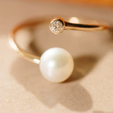 Zoe Chicco 14kt Gold Pearl and Diamond Bezel Bypass Wrap Ring laying on a table
