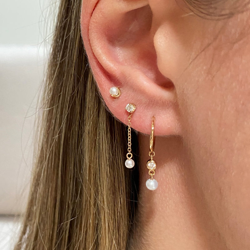 woman's ear wearing Zoë Chicco 14kt Gold Prong Diamond & Tiny Pearl Chain Drop Earrings