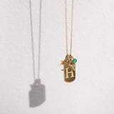 Zoe Chicco 14karat gold chain with a dog tag engraved with H, a Midi Bitty Star charm, an emerald bezel charm, and a pave diamond lightning bolt charm