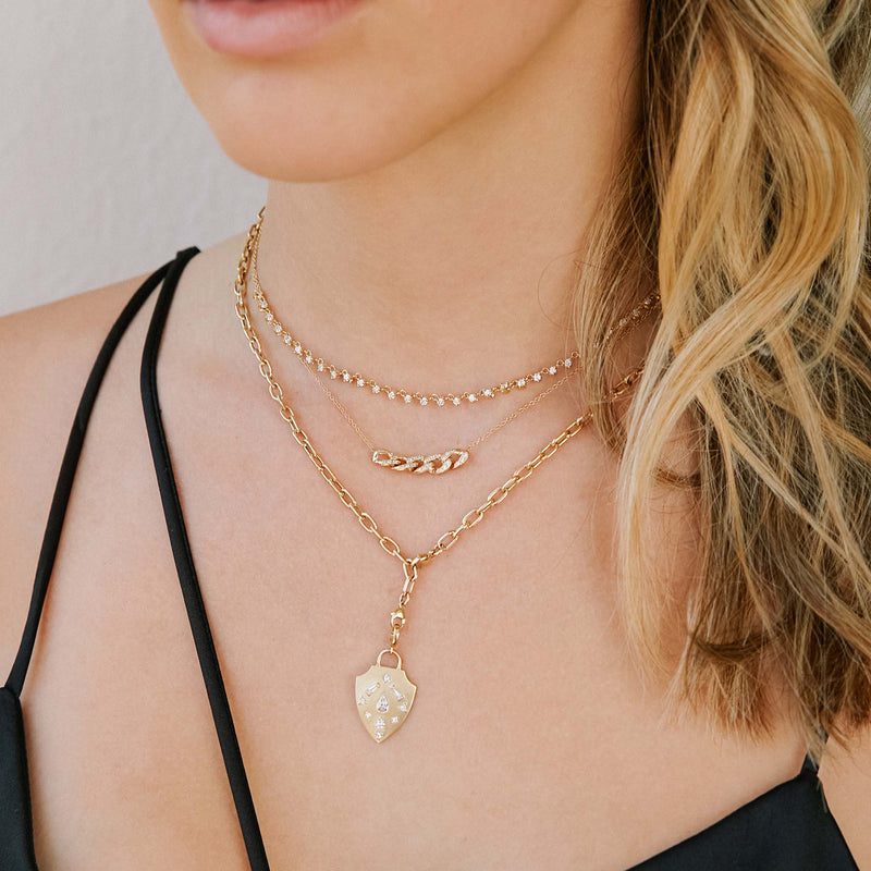 woman in black top wearing a Zoë Chicco 14k Gold Diamond Mosaic Brushed Gold Shield Adjustable Chain Necklace layered with two other necklaces