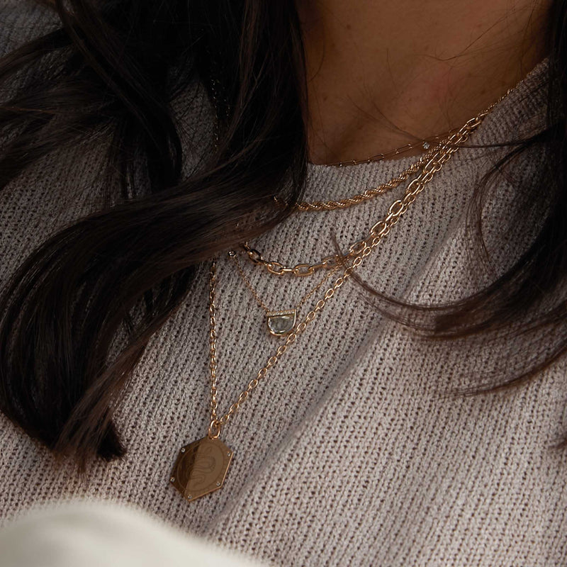 close up of woman in taupe grey knit top wearing a One of a Kind Zoë Chicco 14k Gold Half Moon Rose Cut Diamond with Diamond Stations Necklace layered with a Mixed Cut Diamond Paperclip Chain Necklace, Medium Rope Chain, Medium Square Oval Link Chain Necklace, and a Snake Hex Medallion Square Oval Chain Necklace