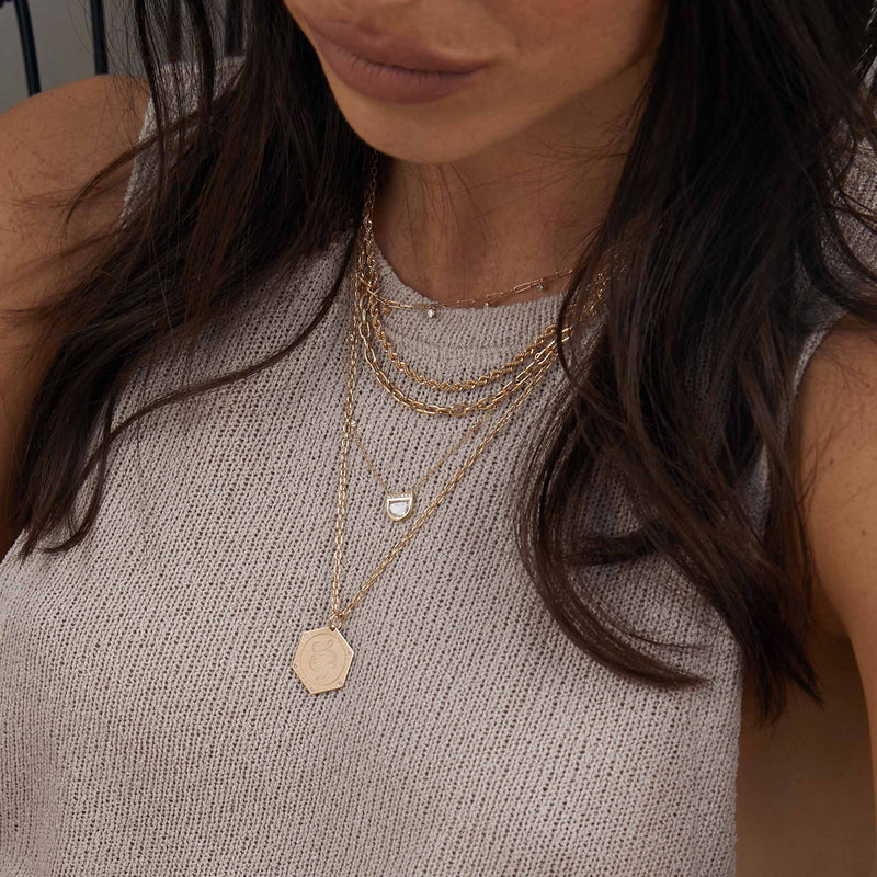 woman in taupe grey knit top wearing a One of a Kind Zoë Chicco 14k Gold Half Moon Rose Cut Diamond with Diamond Stations Necklace layered with a Mixed Cut Diamond Paperclip Chain Necklace, Medium Rope Chain, Medium Square Oval Link Chain Necklace, and a Snake Hex Medallion Square Oval Chain Necklace
