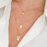 woman in white shirt wearing a Zoë Chicco 14k Gold Pavé Diamond Small Square Edge Dog Tag Charm Pendant on a bar and cable chain necklace