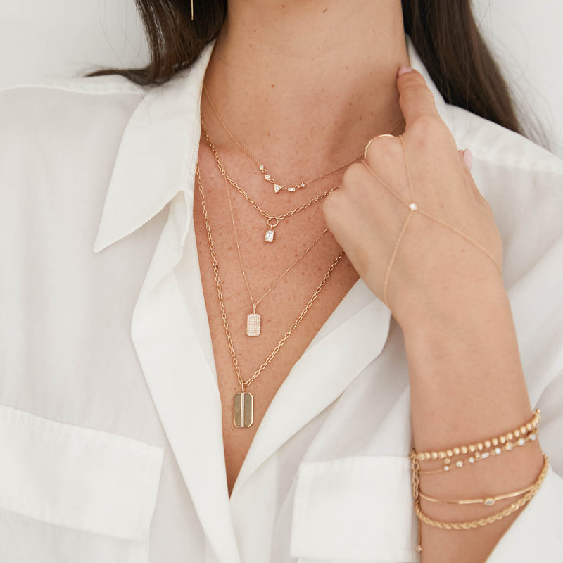 woman in white shirt wearing a Zoë Chicco 14k Gold Pavé Diamond Small Square Edge Dog Tag Necklace layered with three other necklaces