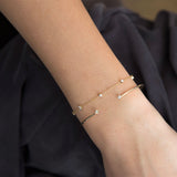 woman's wrist wearing Zoë Chicco 14kt Gold Paris Mixed Diamond Station Bracelet stacked with a cuff bracelet