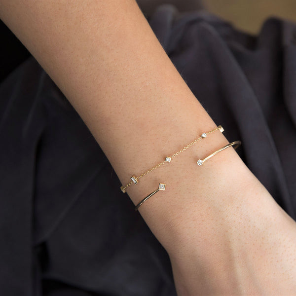 woman's wrist wearing Zoë Chicco 14kt Gold Paris Mixed Diamond Station Bracelet stacked with a cuff bracelet