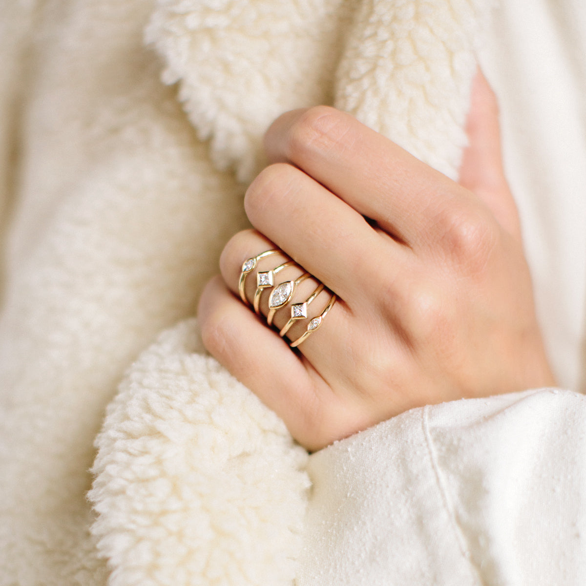 Close up of a hand wearing a Zoe Chicco 14k gold and diamond ring with mutiple bands on a white background
