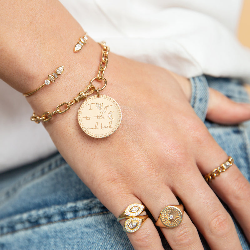woman resting hand on her side wearing a Zoë Chicco 14k Gold "I Love You To The Moon & Back" Mantra XL Square Oval Link Chain Bracelet on her wrist
