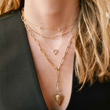 woman in black vest wearing a Zoë Chicco 14k Gold 5 Graduated Diamond Trio Station Necklace layered with three other necklaces