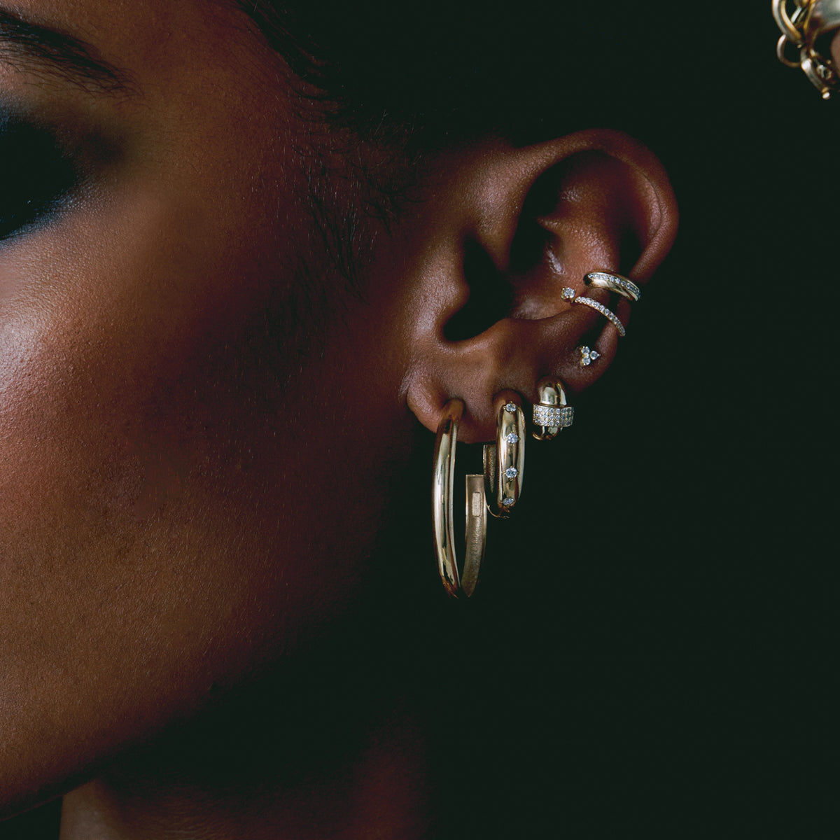 close up of woman's ear wearing Zoë Chicco 14k Gold Pavé Diamond Line Chubby Ear Cuff with various other Chubby hoop and cuffs