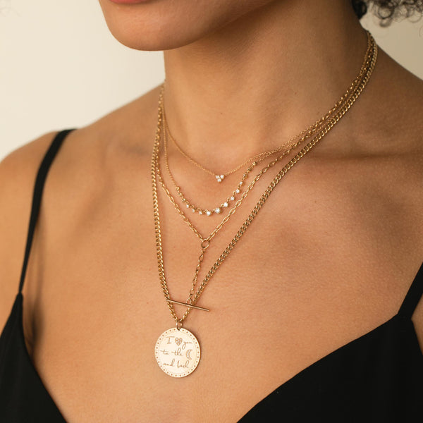 woman in black camisole top wearing a Zoë Chicco 14k Gold Prong Diamond Trio Necklace layered with a 15 Linked Graduating Prong Diamond Necklace, Small Square Oval Link Chain Faux Toggle Lariat Necklace, and a Large "I love you to the moon & back" Mantra Small Curb Chain Necklace