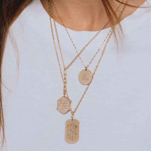 woman in white t-shirt wearing Zoë Chicco 14k Gold Mantra Dog Tag with Diamond Bail Square Oval Chain Necklace layered with two necklaces