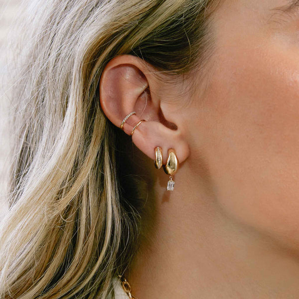woman's ear wearing a Zoë Chicco 14k Gold Emerald Cut Diamond Small Aura Huggie Hoop Earring 