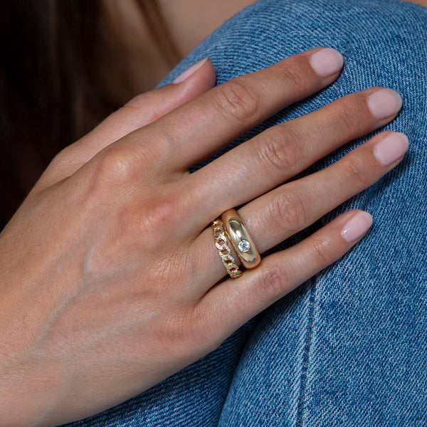 woman's hand resting on jeans wearing Zoë Chicco 14k Gold Round Diamond Small Aura Ring stacked with a Pave Diamond Medium Curb Chain Ring on her ring finger
