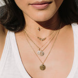 woman wearing Zoe Chicco 14kt gold mantra and amore necklaces layered with rondelle bead necklaces