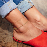 woman in jeans wearing Zoë Chicco 14kt Gold 7 Dangling Diamond Anklet and Small Curb Chain Floating Diamond anklet on her ankle