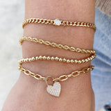 wrist with a stack of yellow gold chain and beaded bracelets with diamonds