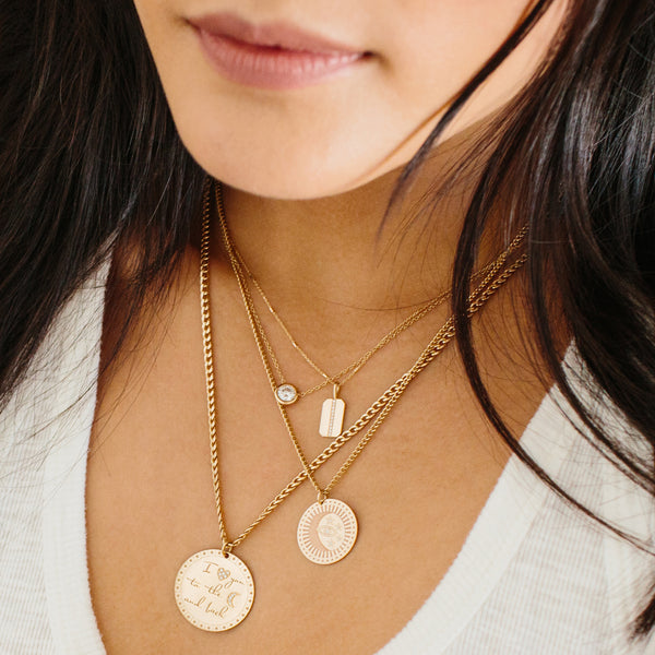 close up of woman in white top wearing Zoë Chicco 14kt Gold Large Pavé Diamond Mantra Medallion Disc Charm engraved with I "heart" you to the "moon" and back on a curb chain necklace