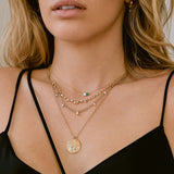 woman in a black camisole top wearing a Zoë Chicco 14k Gold Pear Emerald & Emerald Cut Diamond Necklace layered with three necklaces