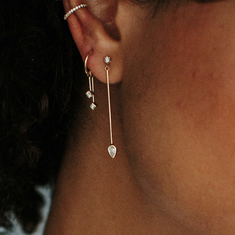 woman's ear wearing Zoë Chicco 14k Mixed Diamond Mobile Dangling Bar Thin Huggie Hoops