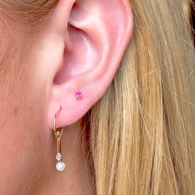 woman's ear wearing Zoë Chicco 14kt Gold Dangling Diamond & Tiny Pearl Bar Huggie Hoops