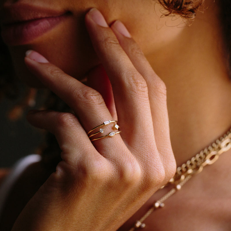 woman resting her hand on her chin wearing Zoë Chicco 14kt Gold 3 Thin Band Mixed Diamond Ring on her ring finger