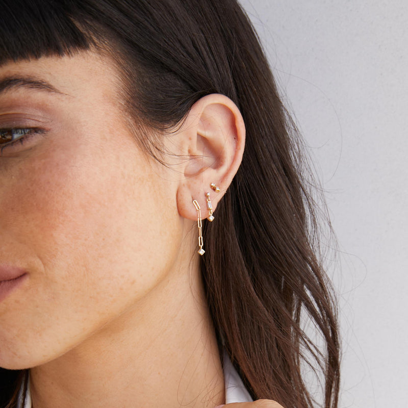 close up of brunette woman's ear wearing a Zoë Chicco 14k Gold Paperclip Chain with Princess Diamond Drop Earring with a 3 Linked Mixed Diamond Short Drop Earring and Mixed Prong & Princess Diamond Stud