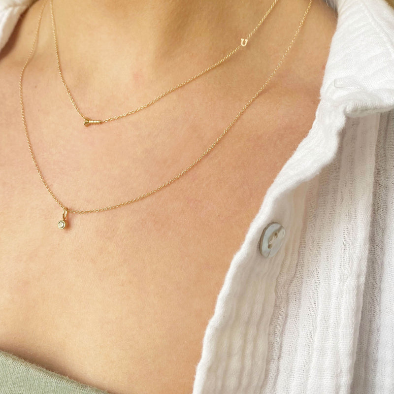 woman in white shirt wearing Zoë Chicco 14k Gold Screw "U" Station Chain Necklace layered with a Diamond Bezel Pendant Necklace