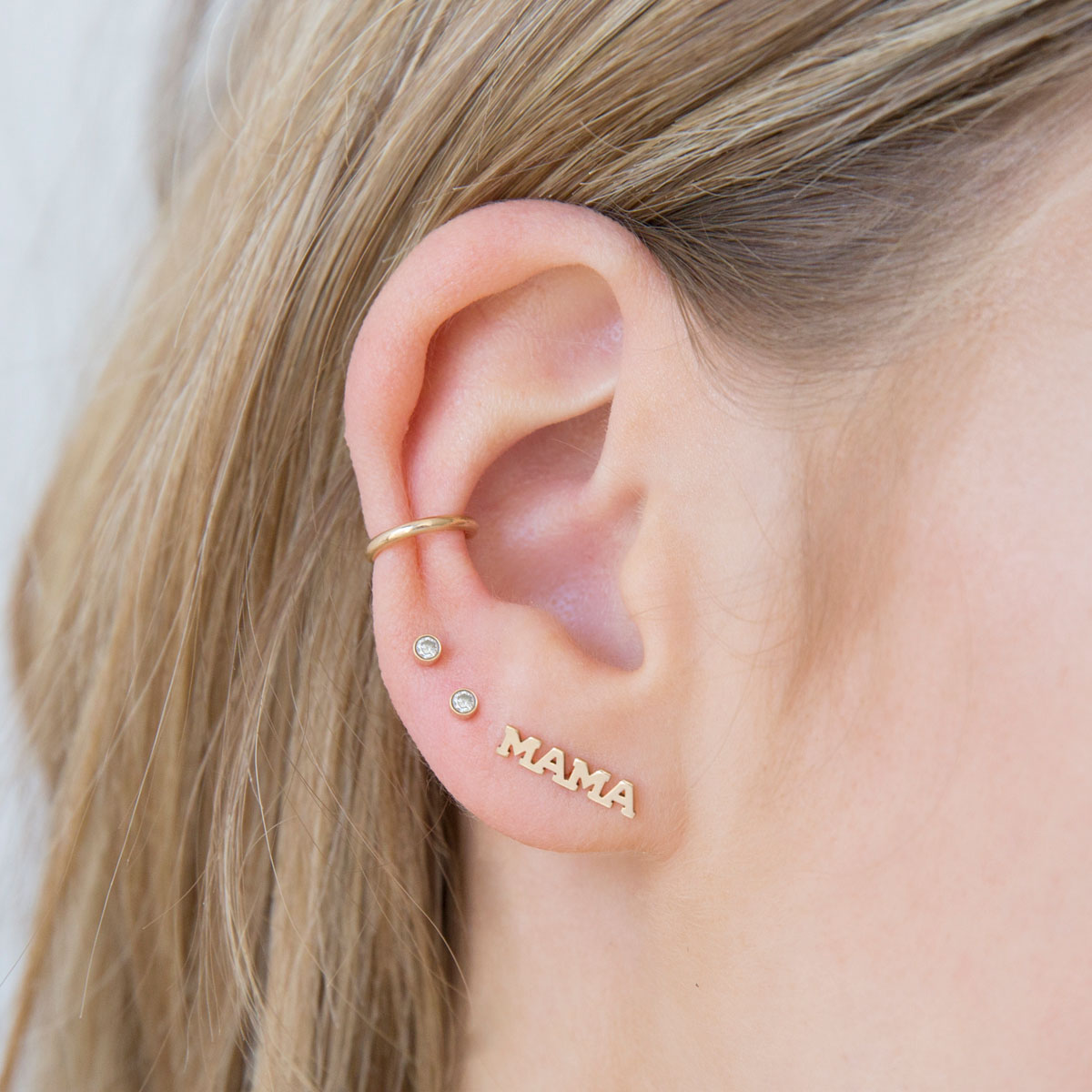woman's ear wearing Zoe Chicco 14kt Gold Thick Plain Ear Cuff with two diamond bezel studs and a MAMA stud