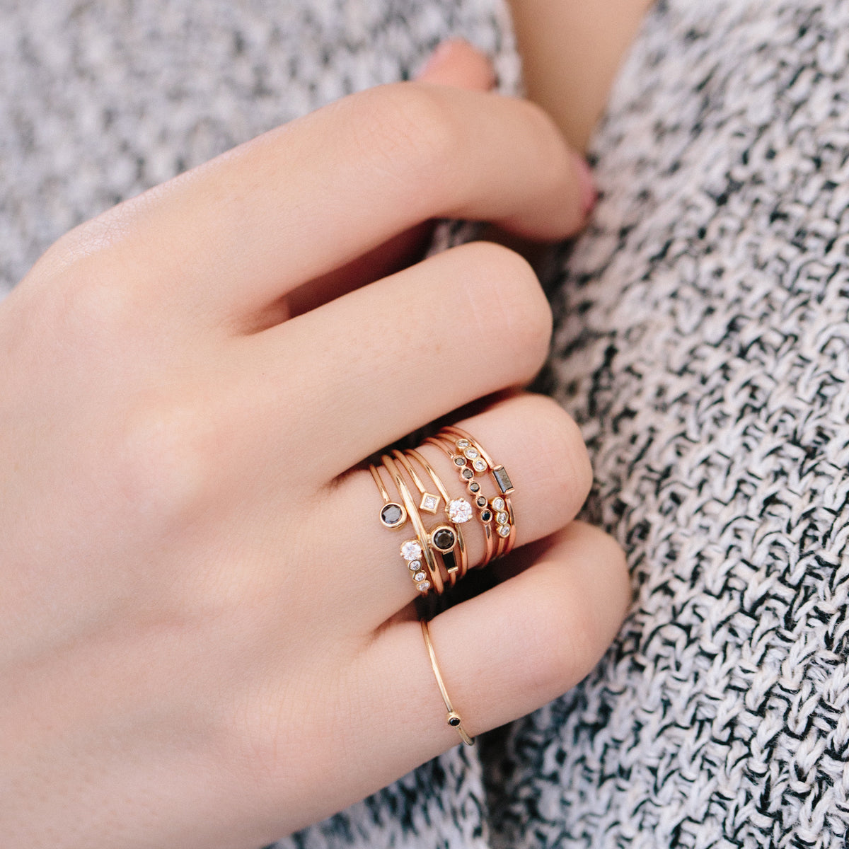 woman's hand wearing Zoë Chicco 14kt Gold Single Prong Diamond Solitaire Ring stacked with  black diamond rings