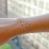 close up of woman's wrist wearing Zoë Chicco 14kt Gold Paris Mixed Diamond Station Bracelet stacked with other fancy cut diamond bracelets
