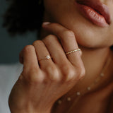 woman wearing a Zoë Chicco 14k Gold Tiny Diamond Gold Bead Eternity Ring on her index finger