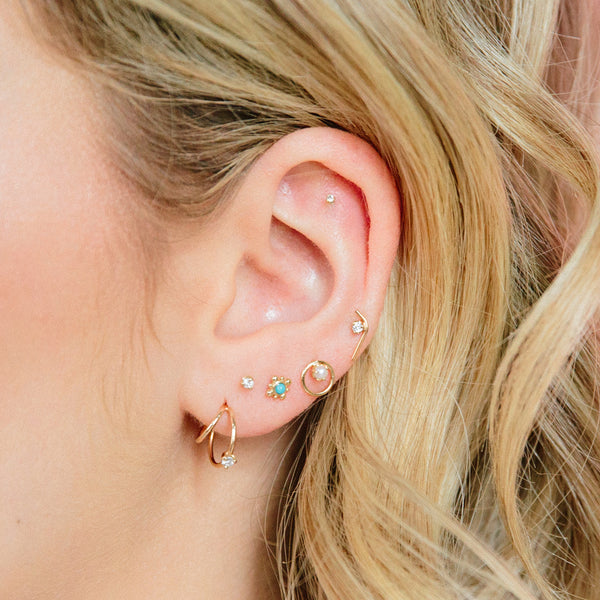 woman's ear wearing Zoe Chicco 14kt Gold Prong Set Diamond Check Mark Stud Earrings with five other stud earrings